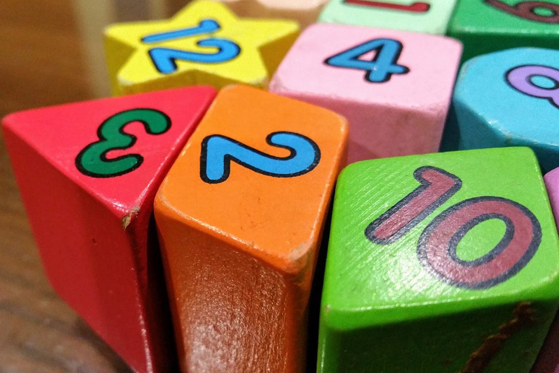 A close-up of colorful wooden blocks with numbers 2, 3, 4, 10, and 12, plus a yellow star-shaped block, arranged on a table - airbnb family friendly