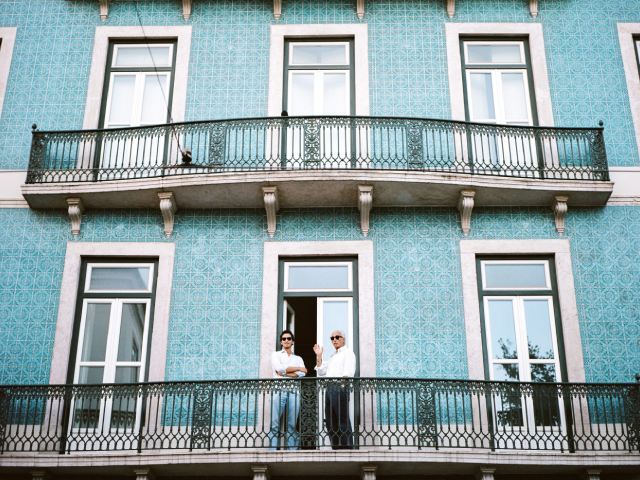 Deux personnes se tiennent debout et regardent le balcon du deuxième étage d'un bâtiment bleu avec des balustrades ornées et des carreaux à motifs - airbnb vacances noel