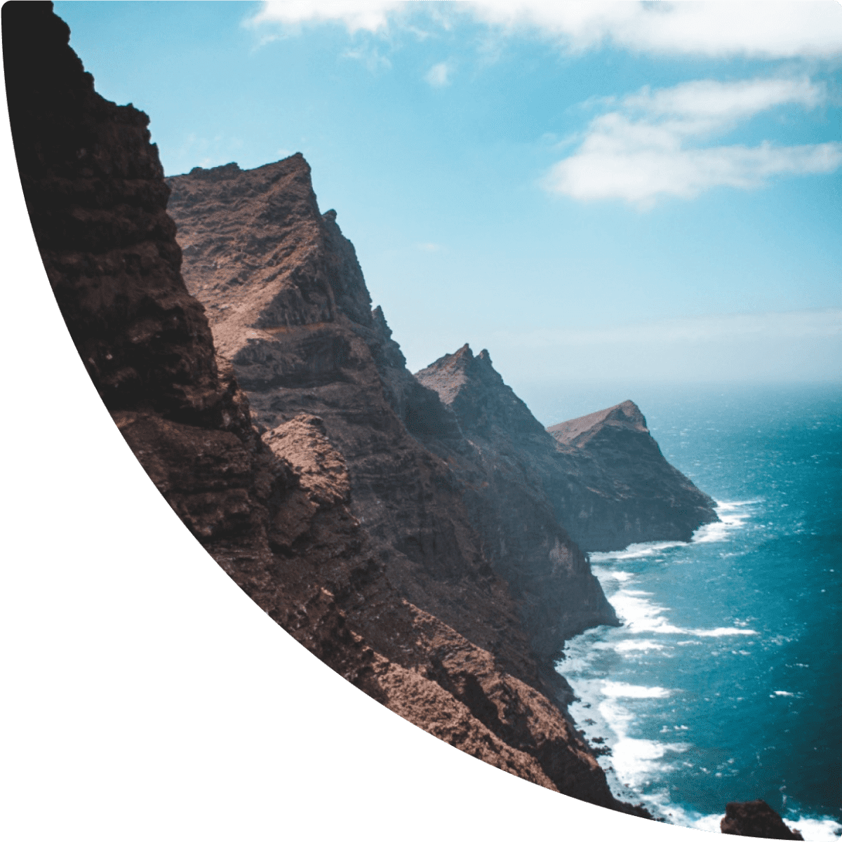 a rocky cliff side with water in the background