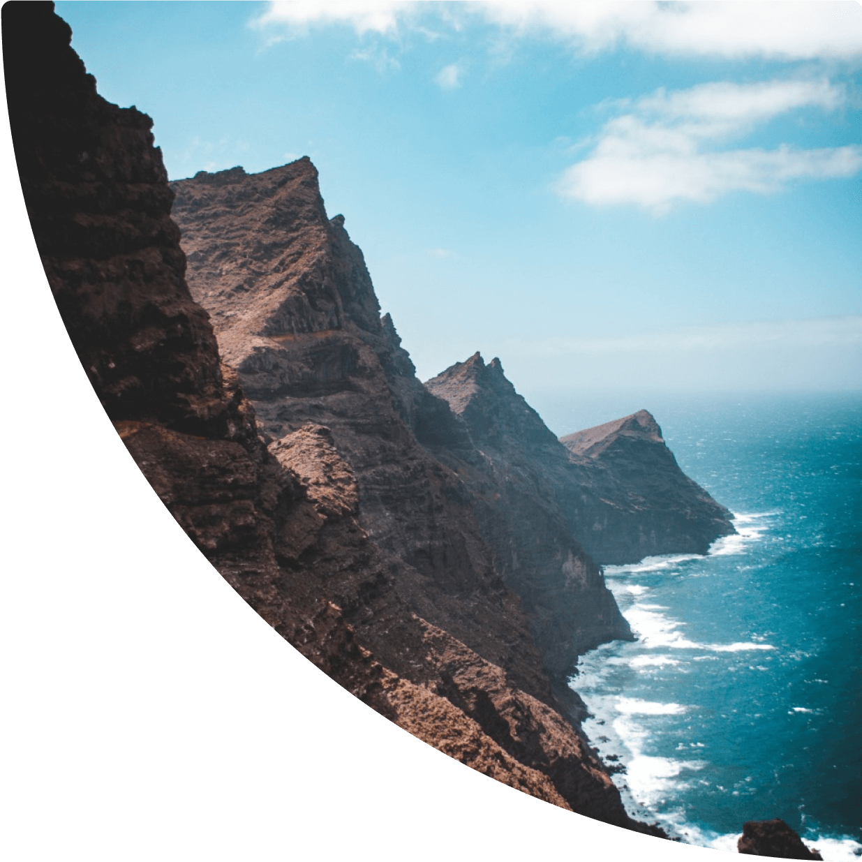 a rocky cliff side with water in the background