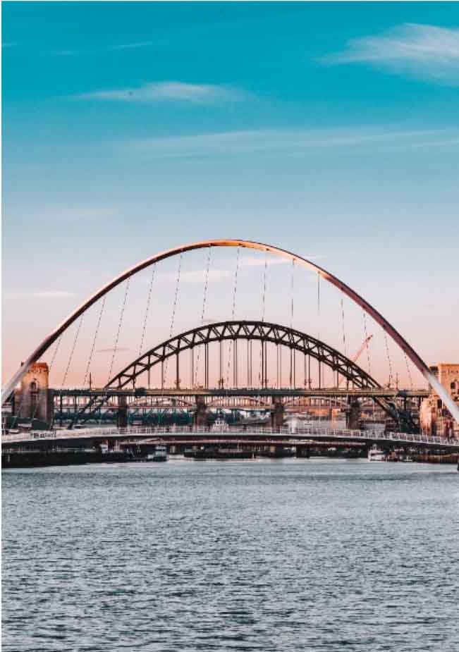 a bridge over water with a bridge and buildings in the background