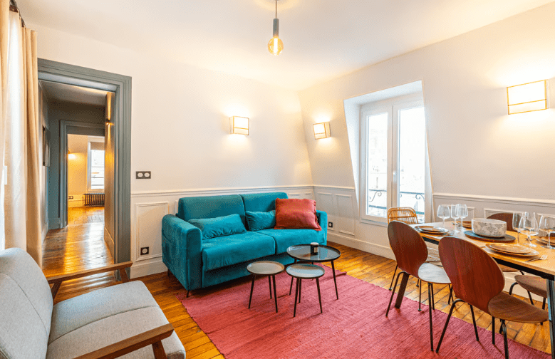 a living room with a blue couch and a table and chairs