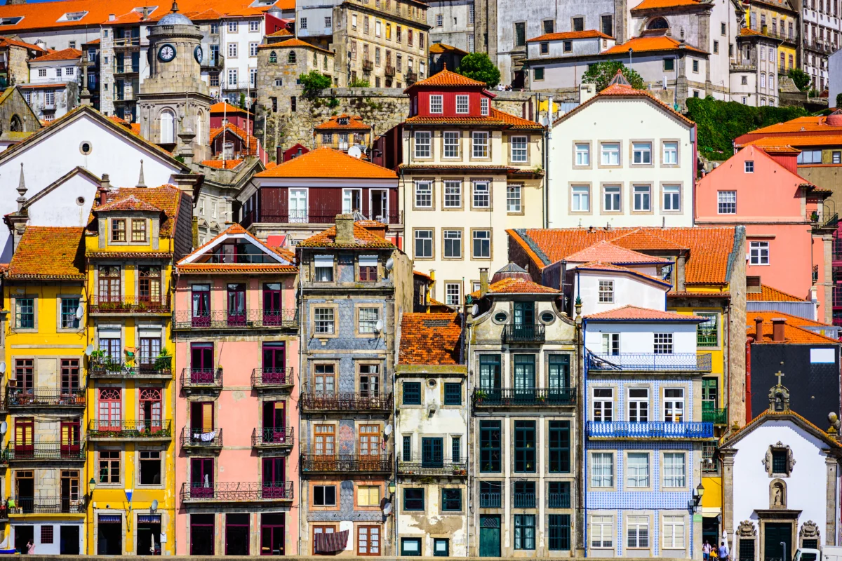 Colorful historic buildings with tiled façades and red roofs tightly packed along a Porto hillside - Porto city break