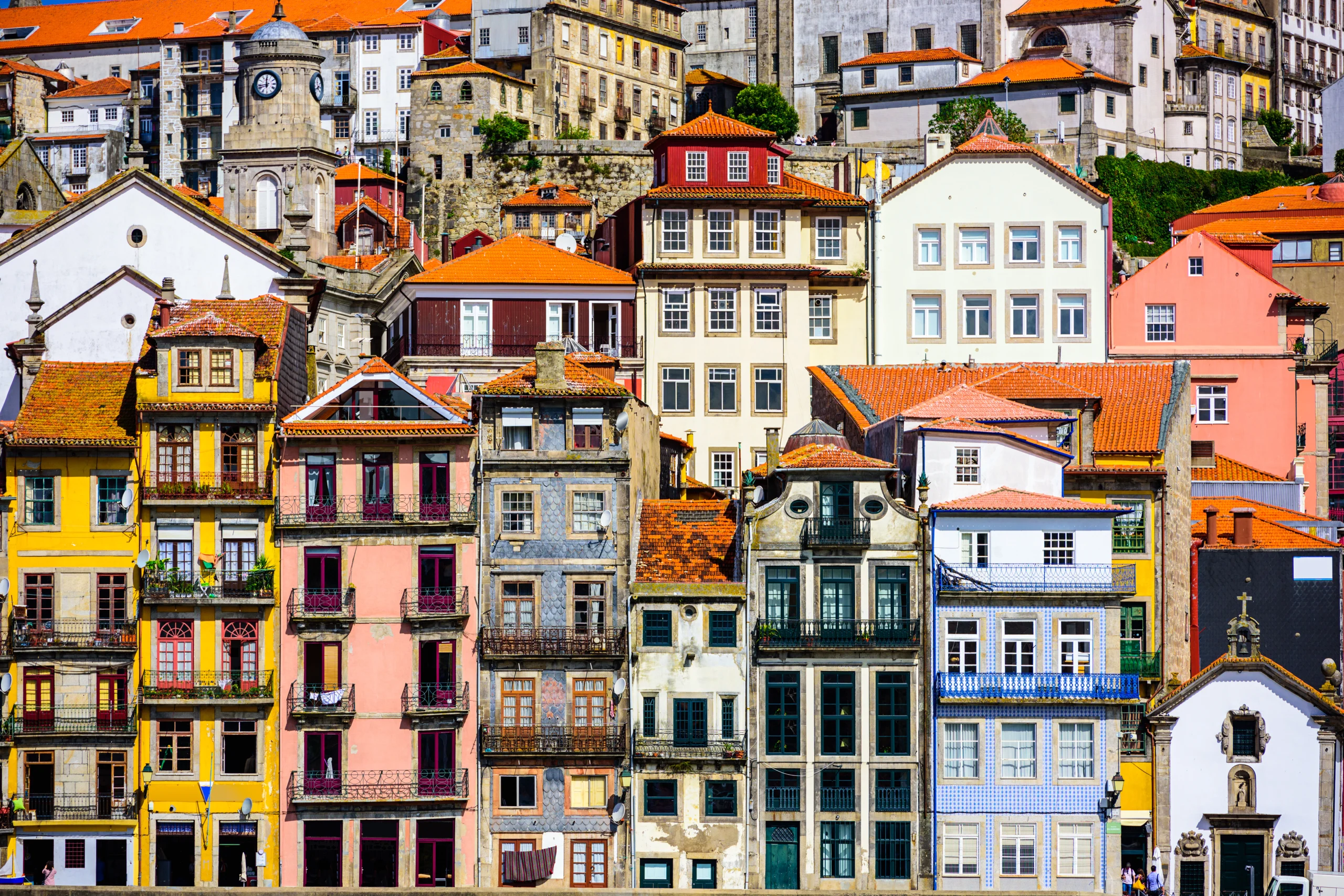 Colorful historic buildings with tiled façades and red roofs tightly packed along a Porto hillside - Porto city break