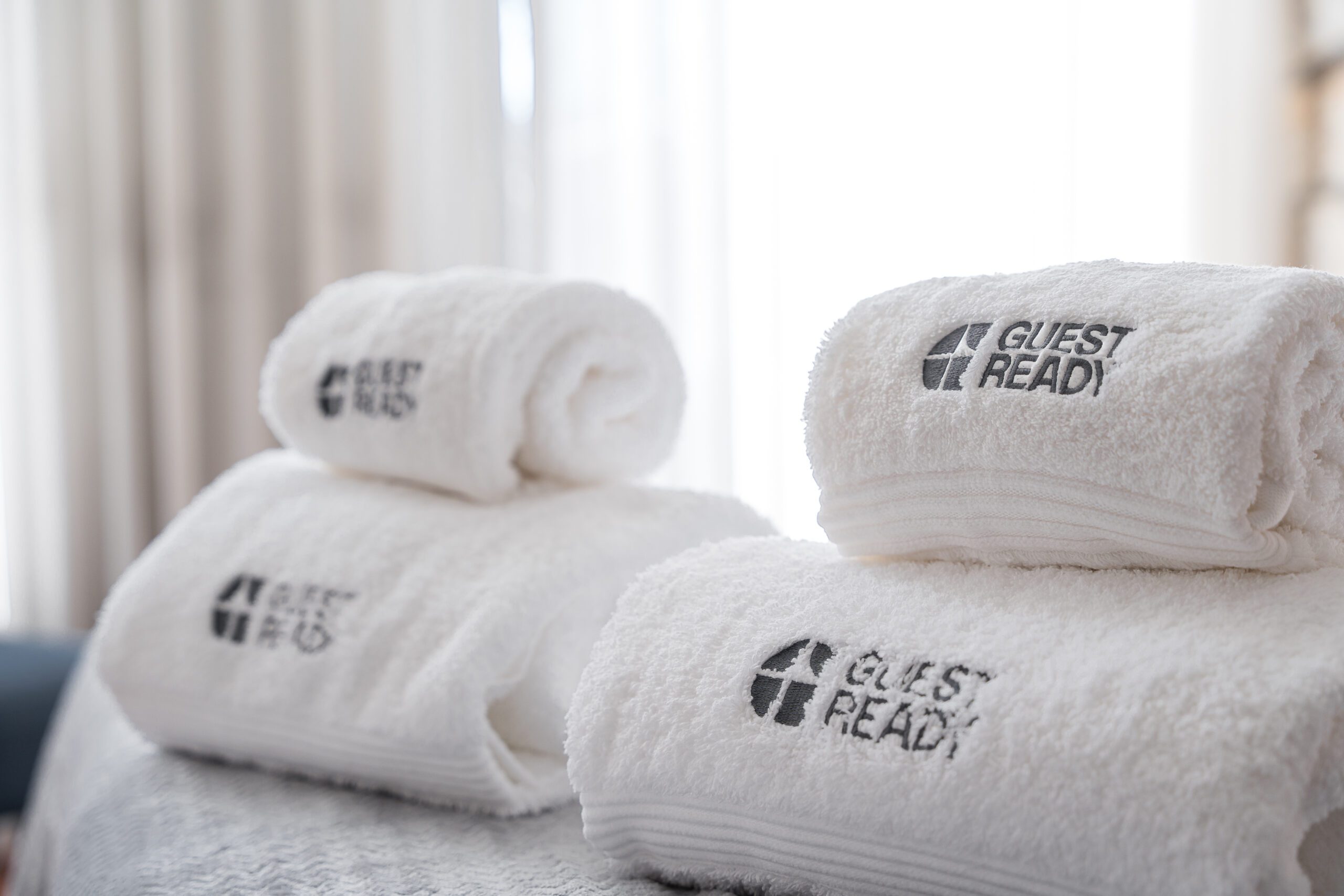 Toalhas brancas com logótipo GuestReady em alojamento, exemplo de qualidade oferecida por empresas de gestão de alojamento local.