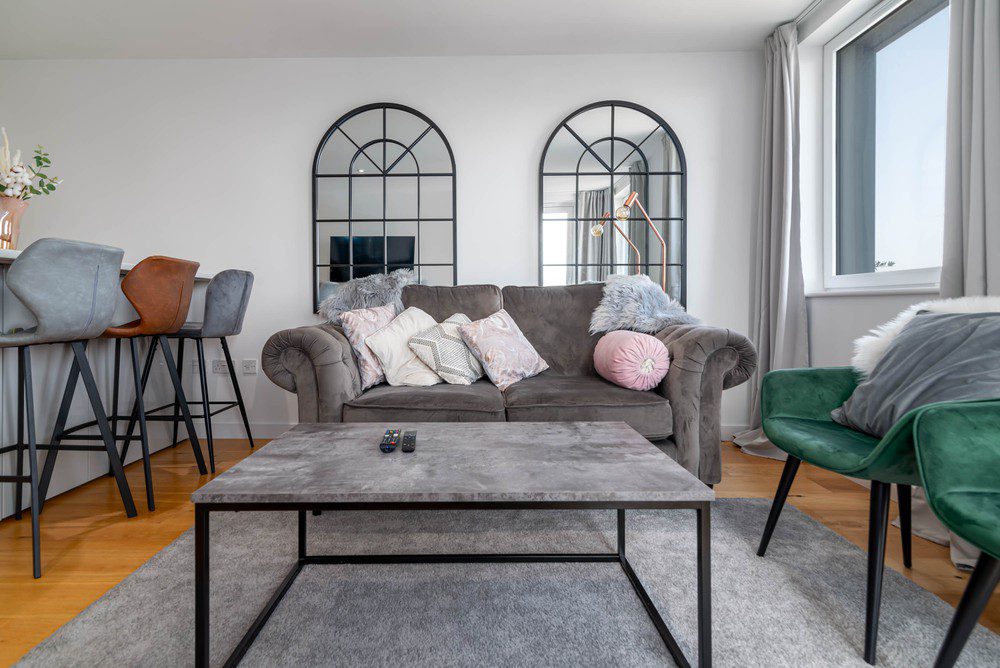 Modern living room in a furnished apartment, ideal for a second home short term rental with comfortable seating, dining area, and bright natural light.