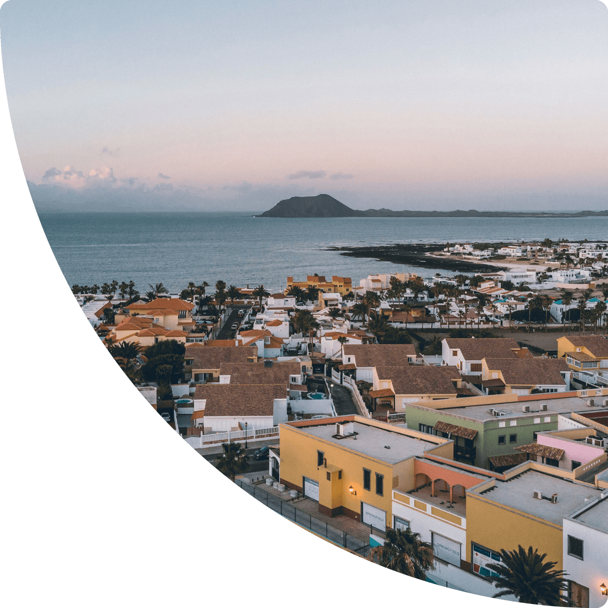 Panoramic view of a coastal village with the ocean at sunset