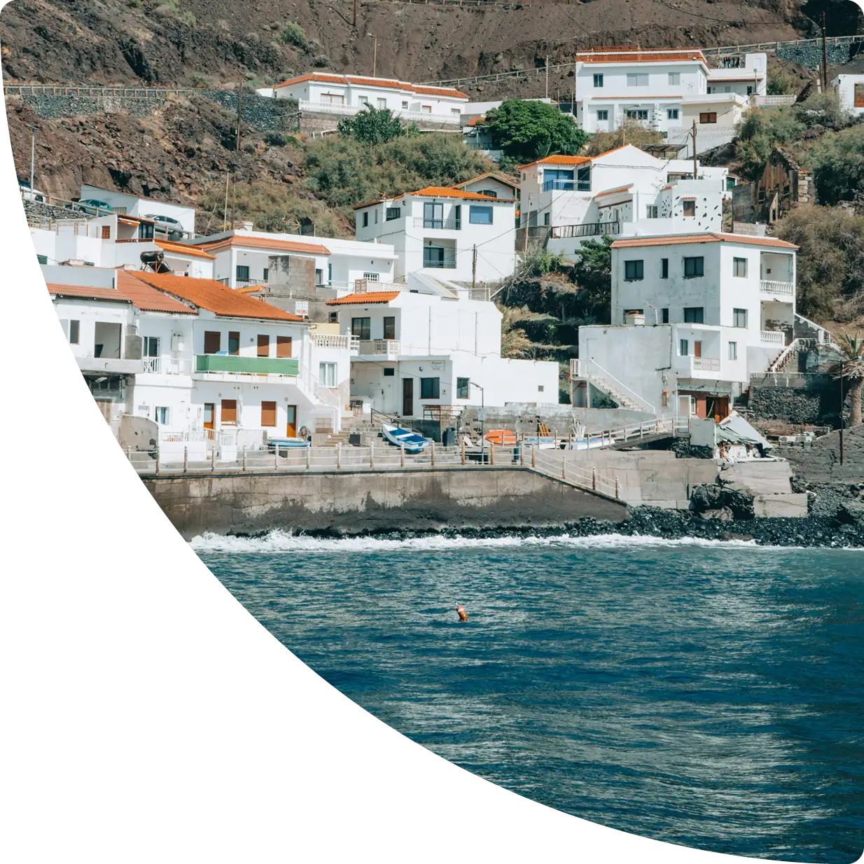 Casas blancas con tejados rojos junto al mar, al pie de una ladera - gestión de apartamentos turísticos en La Gomera