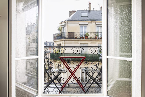 Location moyenne durée à Paris : vue depuis un balcon avec petite table et chaises, donnant sur des immeubles parisiens.
