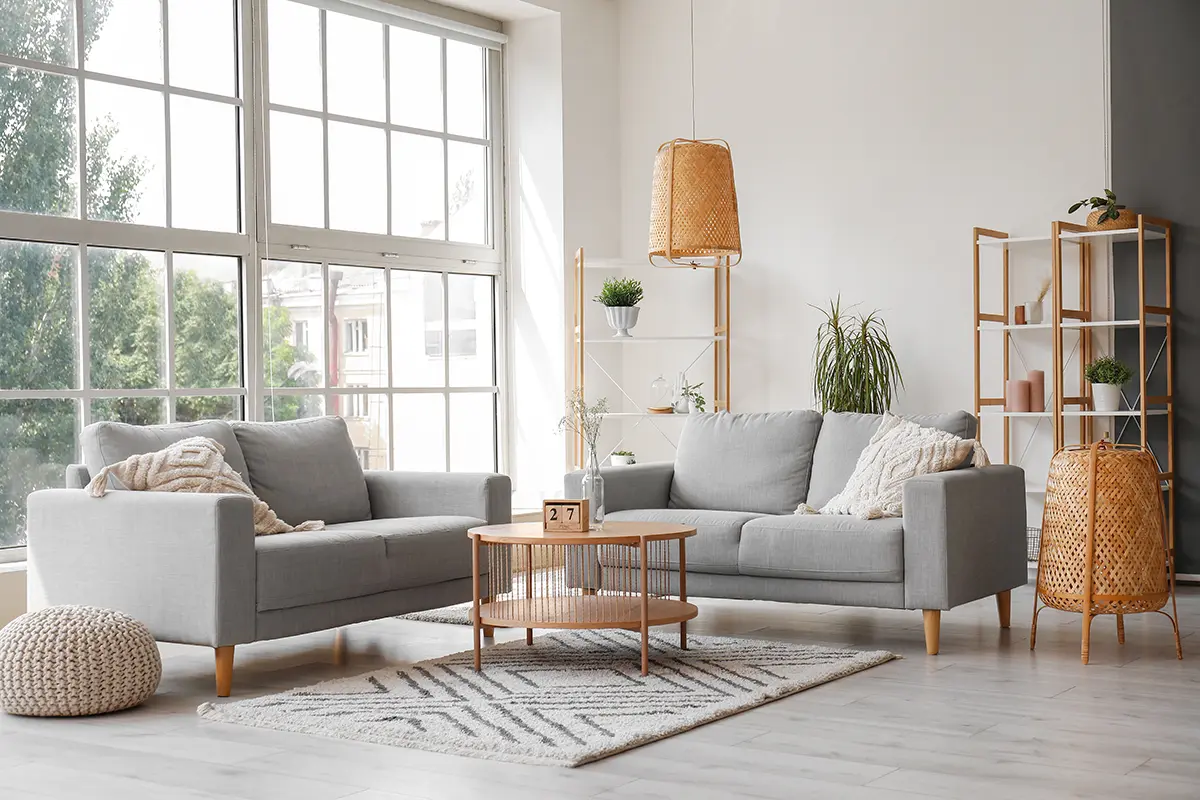 Bright living room with two grey sofas, a wooden coffee table, and large windows.
