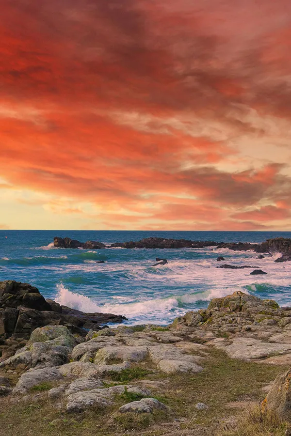 Sunset over a rocky Atlantic coastline with crashing waves - airbnb management La Baule