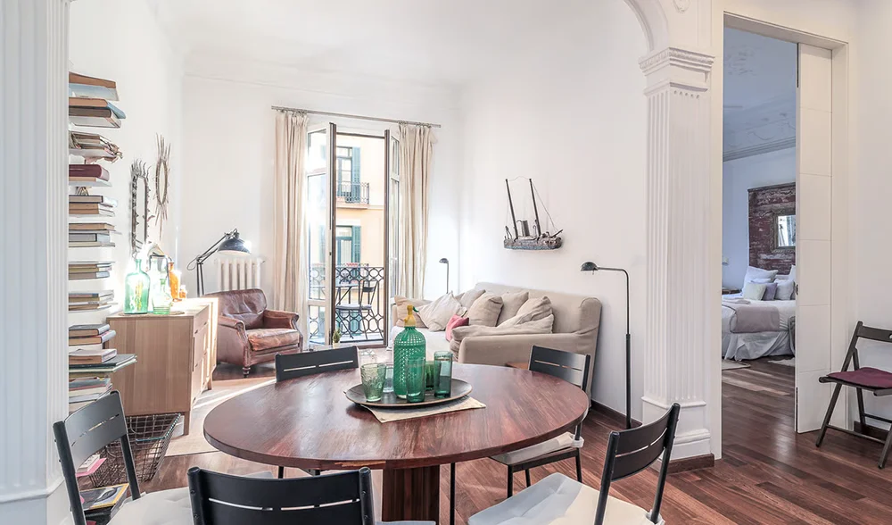 Salón luminoso con mesa redonda y balcón en apartamento moderno, gestion integral del alquiler